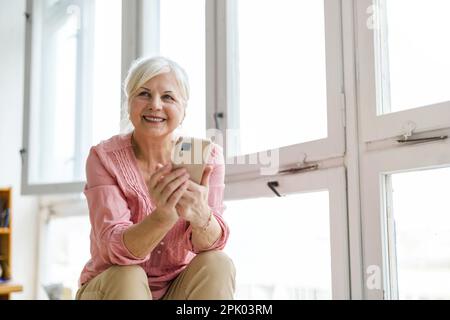 Smiling senior woman using smartphone Banque D'Images