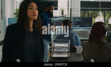 Programmeurs de logiciels parlant d'algorithmes sur grand écran et tablette, analysant le langage de script html. Équipe d'ingénieurs système discutant de la base de données sur la fenêtre du terminal, l'interface du serveur. Banque D'Images