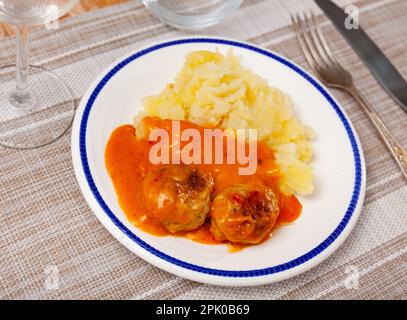 assiette ronde blanche avec boulettes de viande saupoudrées d'aneth haché dans une sauce tomate avec purée de pommes de terre Banque D'Images