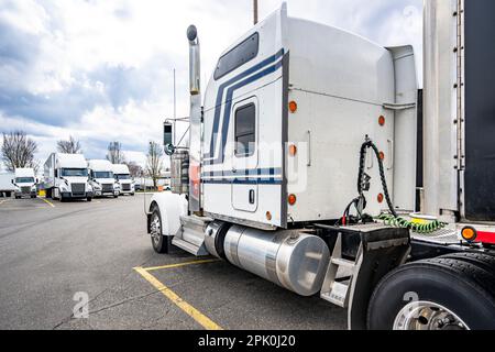 Grand rig de classe industrielle capot américain classique semi-camion blanc avec cabine allongée pour le confort du conducteur de camion debout sur l'aire de stationnement d'arrêt de camion op Banque D'Images