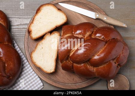 Couper du pain tressé fait maison et un couteau sur une table en bois, poser à plat. Challah pour Shabbat Banque D'Images