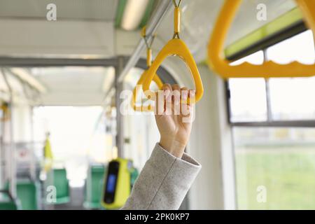 Femme tenant la poignée dans les transports en commun, gros plan Banque D'Images