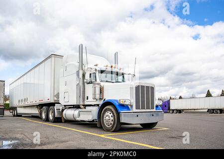 Grand rig industriel capot américain classique semi-camion blanc avec cabine allongée pour le confort du conducteur de camion reposer debout avec semi-remorque de camionnette sèche o Banque D'Images