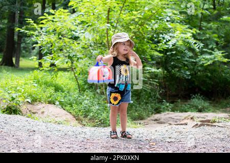 Une petite fillette du caucase a attrapé un insecte lors de la promenade dans la nature. Enfant explorant les insectes. Randonnée avec un tout-petit. Enfant explorant la nature. Banque D'Images