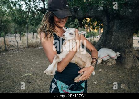 elle tient un agneau sur ses mains et élevage de moutons ferme. Photo de haute qualité Banque D'Images