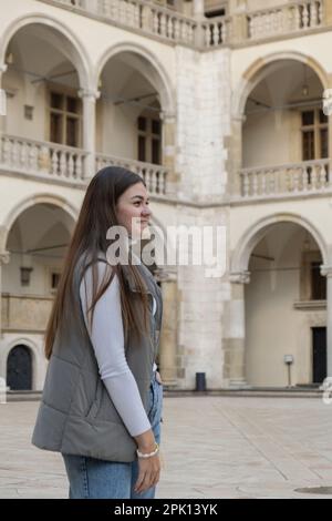 Une femme voyageur dans des lieux historiques regarde autour de la cour d'un monument dans le château de Krakow Wawel. Tourisme dans un lieu historique le jour ensoleillé. Femme Tourisme et blogging partage en direct en ligne pour le voyage de l'auditoire ensemble Banque D'Images