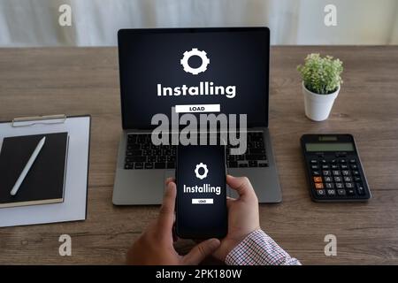 Homme installant la mise à jour de logiciel sur les communications de technologie numérique de téléphone mobile et d'ordinateur portable Banque D'Images