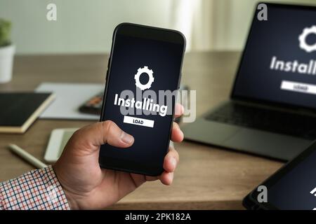 Homme installant la mise à jour de logiciel sur les communications de technologie numérique de téléphone mobile et d'ordinateur portable Banque D'Images