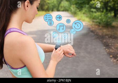 Une jeune femme vérifie le tracker d'activité avec une montre intelligente après un entraînement au parc Banque D'Images