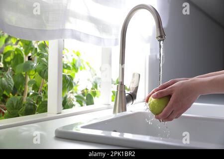 Femme lavant la pomme sur l'évier dans la cuisine, gros plan. Espace pour le texte Banque D'Images