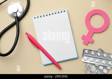 Composition de la pose plate avec le signe de sexe féminin et stéthoscope sur fond beige. Concept de santé des femmes Banque D'Images