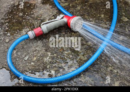 Pulvérisation d'eau à l'extérieur à l'aide d'un tuyau sur une surface en pierre Banque D'Images