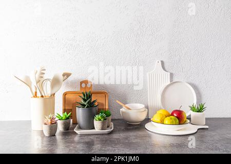 un ensemble de plats divers, outils, un bol de fruits sur un comptoir en pierre face d'un mur texturé gris. espace pour le texte. encore la vie Banque D'Images