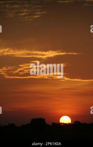 Vue sur le coucher du soleil et le ciel et les nuages imprégnés de teinte orange rougeâtre Banque D'Images