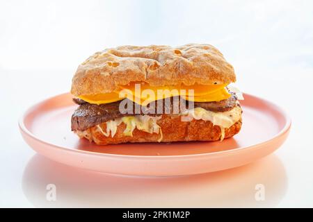 Sandwich ciabatta au steak de Philly servi sur une assiette rose. Banque D'Images