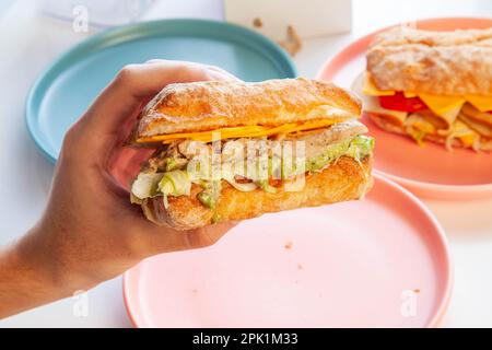 Main tenant le poulet avec l'avocat ciabatta sandwich sain. Banque D'Images