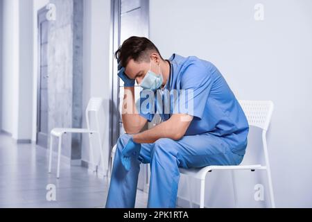 Médecin épuisé assis sur une chaise dans le couloir de l'hôpital Banque D'Images