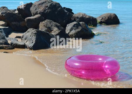 Anneau gonflable lumineux sur la plage de sable près de la mer Banque D'Images