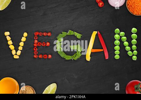 Mot VEGAN fait de différents légumes frais savoureux sur fond noir, plat Banque D'Images