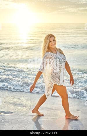 Une promenade sur la plage est exactement ce dont vous avez besoin. une belle femme passant du temps à la plage par une journée ensoleillée. Banque D'Images