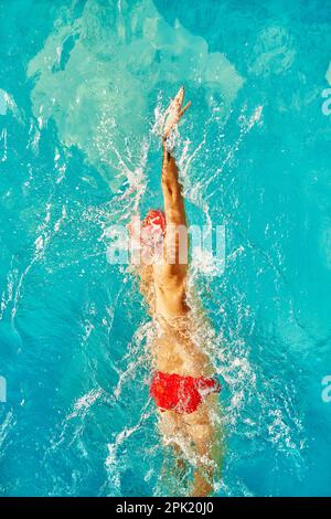 Vue aérienne de dessus Homme nageur natation dans la piscine. Entraînement professionnel de l'athlète pour le championnat, en utilisant Front Crawl, technique Freestyle. À Banque D'Images