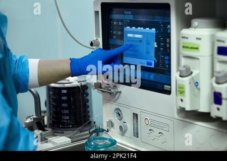 La main du médecin actionne un moniteur de fréquence cardiaque dans un théâtre d'hôpital. Dispositif médical pour la surveillance des signes vitaux dans un hôpital sur un poste de surveillance d'anesthésie Banque D'Images