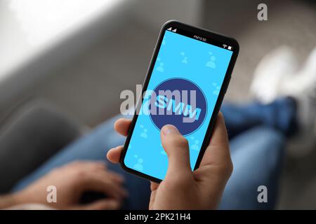 Concept SMM (social Media Marketing). Homme utilisant un smartphone à l'intérieur, gros plan Banque D'Images