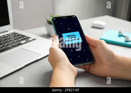 Concept SMM (social Media Marketing). Femme utilisant un smartphone à la table, gros plan Banque D'Images