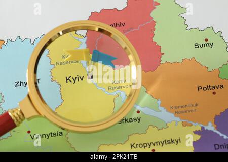Carte de l'Ukraine avec des punaises de drapeau jaune et bleu placées sur Kiev, vue à travers la loupe Banque D'Images