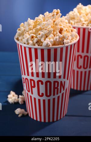 Délicieux pop-corn dans des gobelets en papier sur une table en bois bleu Banque D'Images