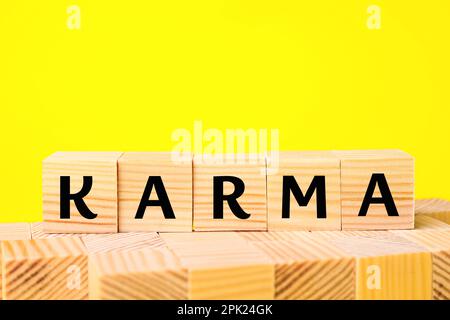 Mot Karma fait de cubes avec des lettres sur fond jaune Banque D'Images