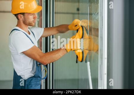 Vue latérale. Jeune homme travaillant en uniforme à la construction pendant la journée Banque D'Images