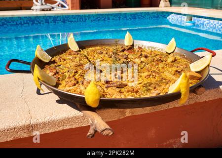 paella traditionnelle avec des tranches de citron décorant à côté d'une piscine Banque D'Images