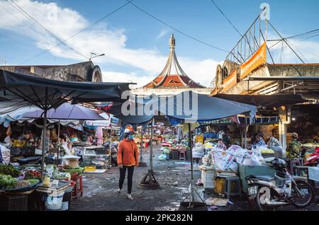 Une cabas femme portant un casque d'accident et un masque facial marche à travers une zone du marché central de Pleiku, dans les Highlands centraux du Vietnam. Banque D'Images