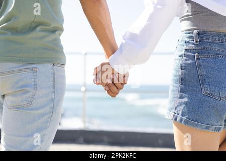 Milieu de couple divers tenant les mains sur la promenade au bord de la mer Banque D'Images