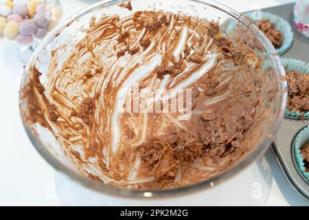 Bol en verre, presque vide, avec des cornflakes de chocolat tout en faisant des mini-nids d'oeufs de chocolat pour Pâques Banque D'Images