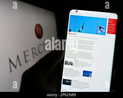 Personne tenant smartphone avec site web de la société Mercuria Energy Group sur écran avec logo. Concentrez-vous sur le centre de l'écran du téléphone. Banque D'Images
