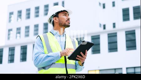 Un ingénieur vérifie les données sur une tablette numérique et inspecte le site de construction. Technicien dans un casque de sécurité faisant de la gestion et de la planification de projet à l'extérieur Banque D'Images