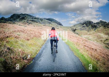 Cycliste de route de sexe masculin en haut du col de Hardnout, Eskdale, Cumbria, Royaume-Uni. Banque D'Images