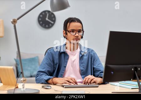 Portrait d'un jeune PROFESSIONNEL DE L'INFORMATIQUE utilisant un ordinateur et écrivant du code sur le lieu de travail de bureau à domicile Banque D'Images