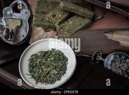 Bangkok, Thaïlande - 17 mars 2023 : bâtonnets de collation faits maison au cannabis sur le carnet de musique ancienne avec les feuilles de cannabis hachées dans la petite assiette de fer b Banque D'Images