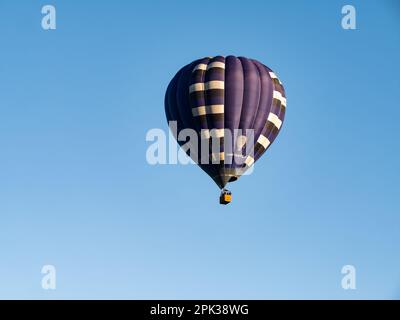 Ballon d'air chaud bleu foncé avec des personnes dans le panier volant dans l'air et ciel bleu sans nuages, pays-Bas Banque D'Images