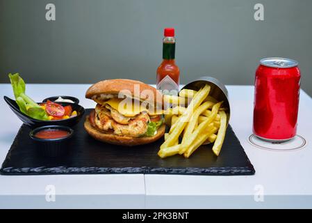 Hamburger de poulet et fromage. Avec salade et boisson non alcoolisée sur un marbre noir Banque D'Images