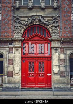 Porte rouge vintage et façade ornée d'un ancien bâtiment historique de Rouen, France. Éléments d'architecture de plein air rustique, grande porte en bois comme m Banque D'Images