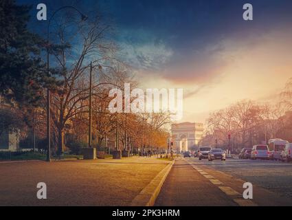 Arc triomphal (Arc de triomphe) à Paris, France. Le célèbre monument historique au coucher du soleil vu de la rue de la ville avec la circulation animée Banque D'Images