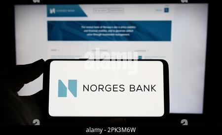 Personne tenant un smartphone avec le logo de la banque centrale norvégienne Norges Bank à l'écran devant le site Web. Mise au point sur l'affichage du téléphone. Banque D'Images