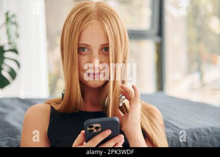 Dans les écouteurs. Une adolescente avec des cheveux blonds est à la maison le jour Banque D'Images