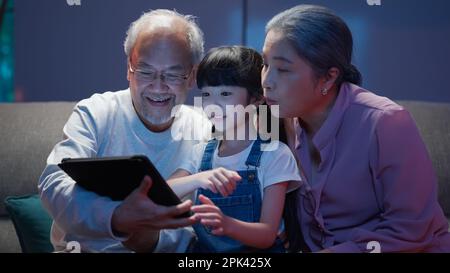 Petite-fille utilisant une tablette avec grand-père senior et grand-mère à la maison Banque D'Images