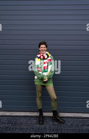 pleine longueur de femme surjoyeuse dans les vêtements de printemps tendance souriant près du mur gris sur la rue urbaine, image de stock Banque D'Images