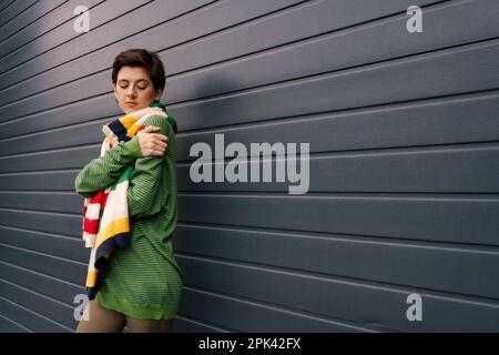 brunette femme en tenue de printemps tendance debout près du mur gris sur la rue urbaine, image de stock Banque D'Images